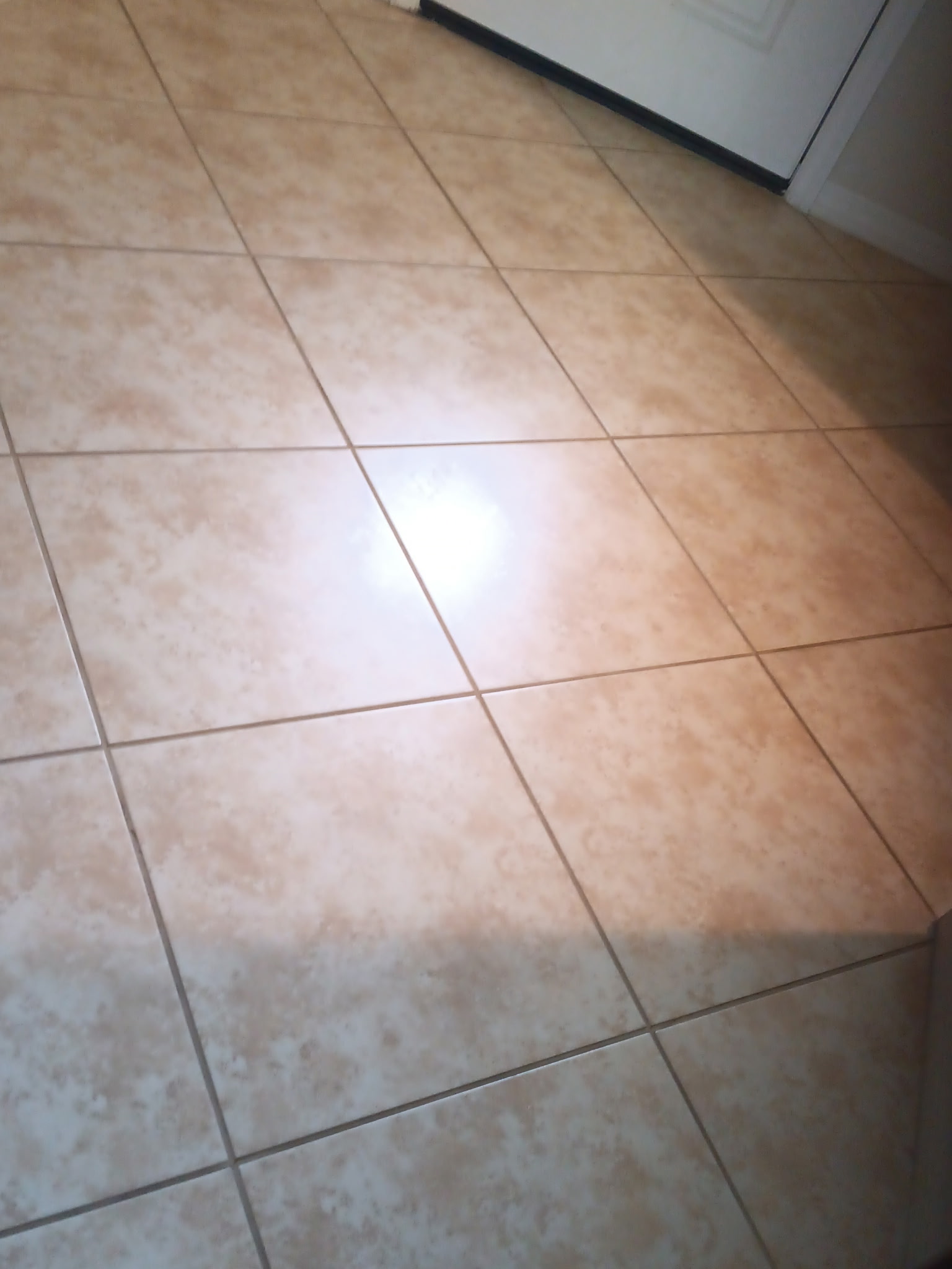Beige tile floor with freshly color-sealed, uniform grout lines